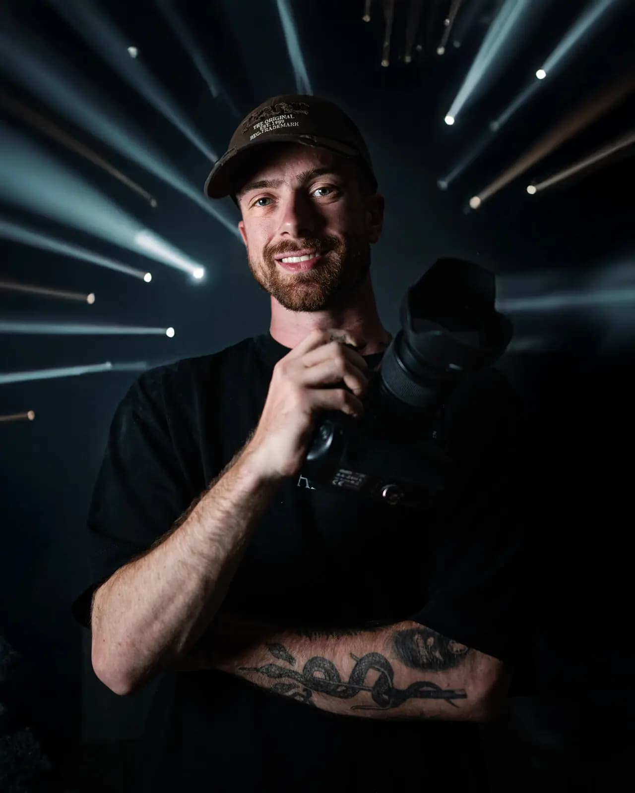 Eric Heitz mit Cap und Kamera, hinter ihm Lichtstrahlen